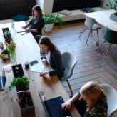 A group of women at a table, with computers and books.