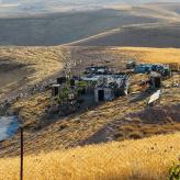 Hills and dunes surrounding houses with tin roofs.